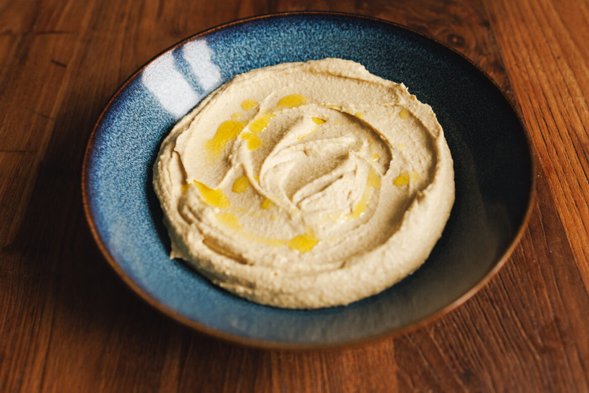 Krémový hummus v hlubokém talíři zakápnutý olivovým olejem