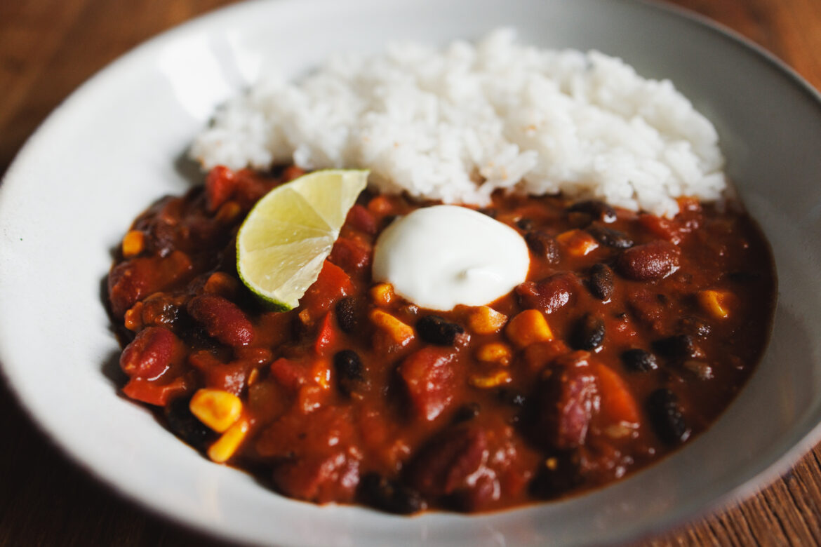 Veganské chilli sin carne ze dvou fazolí, kukuřice a čokolády, s rýží, limetkou a zakysanou veganskou smetanou